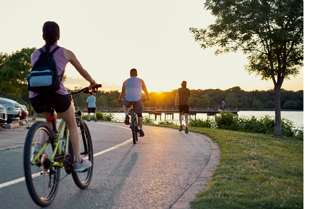 Bikers and runners doing sports over a trail in White Rock lake, Texas during sunset time. De-scale period.